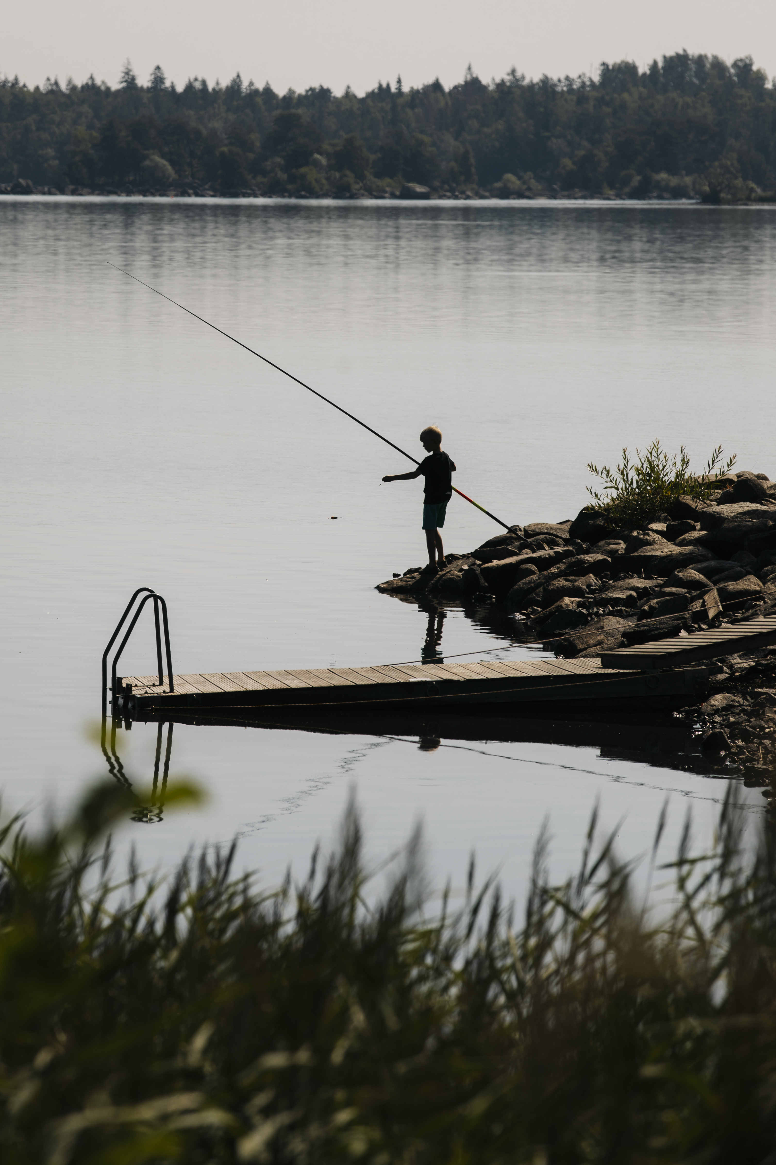 person metar i strandkanten av en sjö i skymningen
