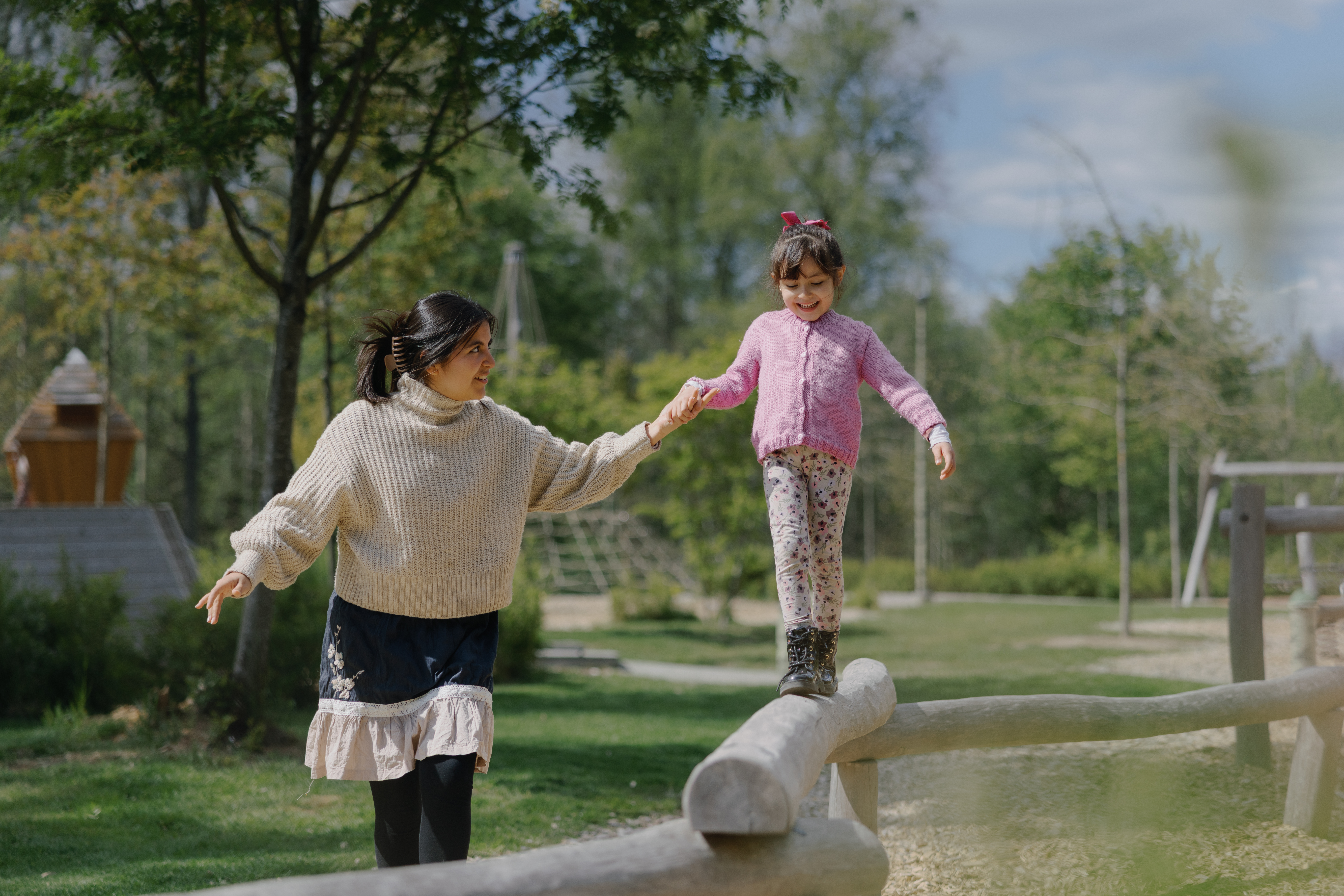 Kvinna håller barn i handen som balanserar på en stock