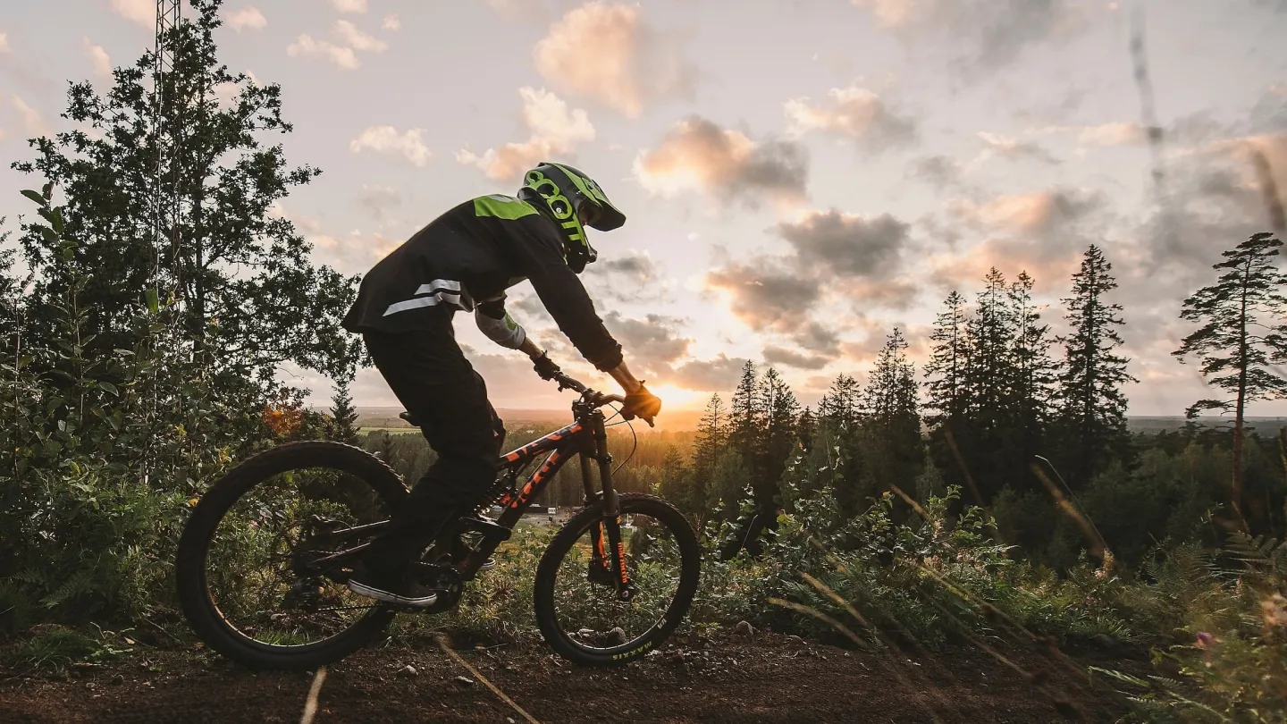 Kille cyklar i skogen under kvällstid