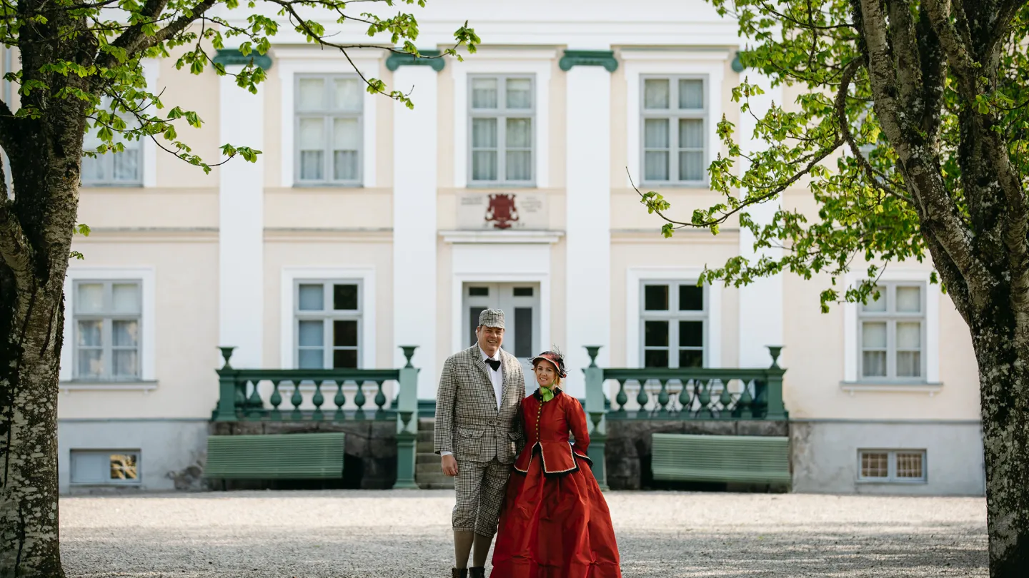 Man och kvinna i historiska kläder står framför slott